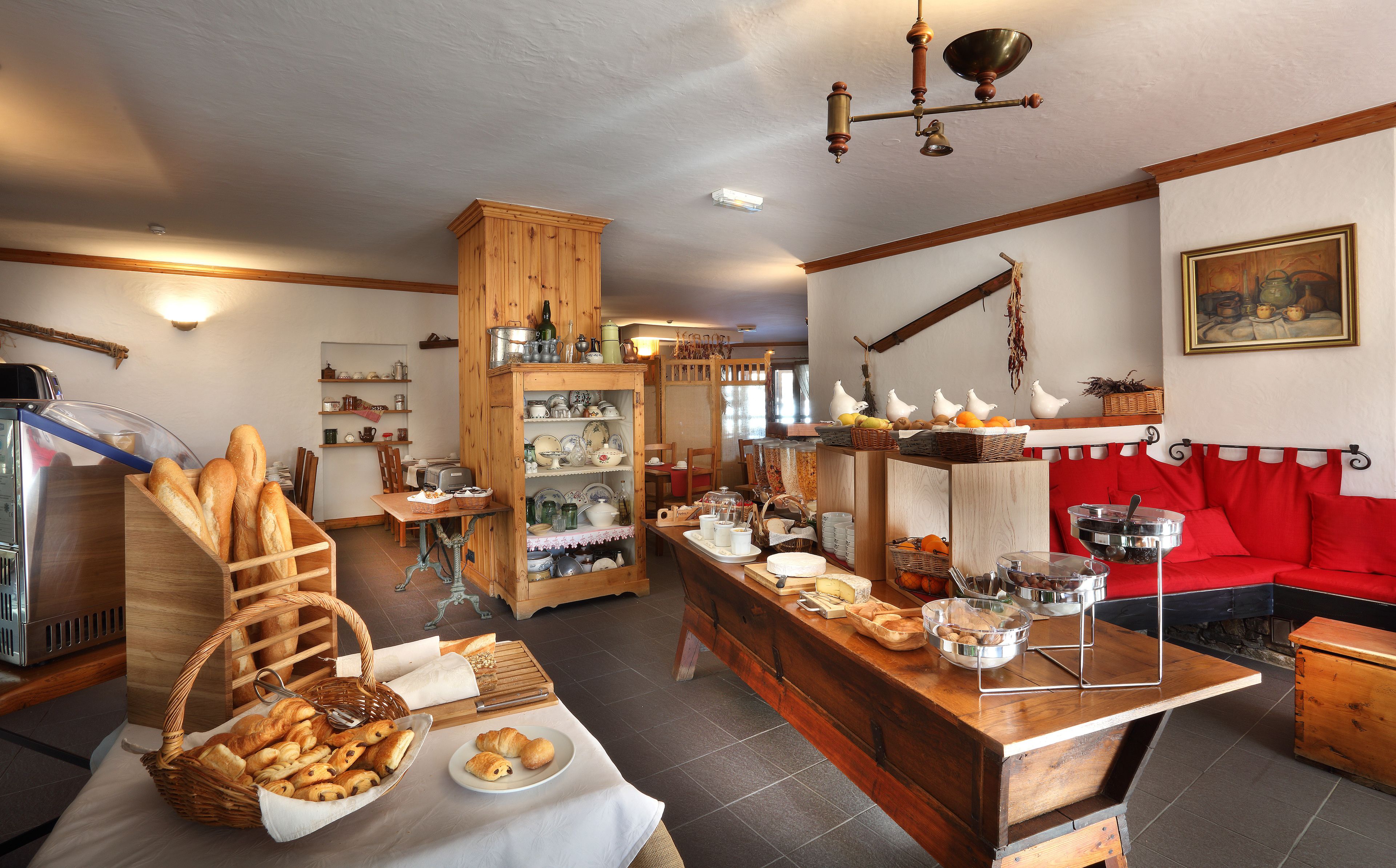 A cozy kitchen with wooden cabinets, a dining area with a red sofa, and various kitchen utensils and appliances.