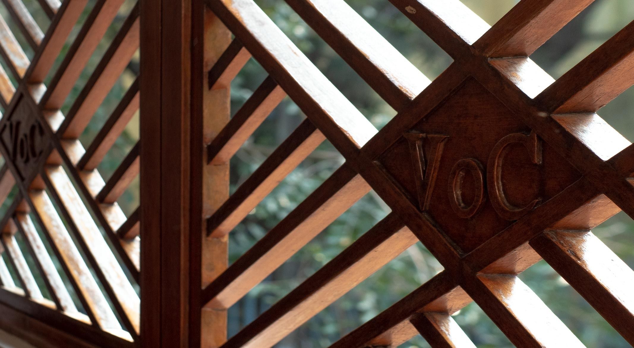 Une structure en treillis de bois, avec une découpe en forme de losange contenant les lettres « VOG ».