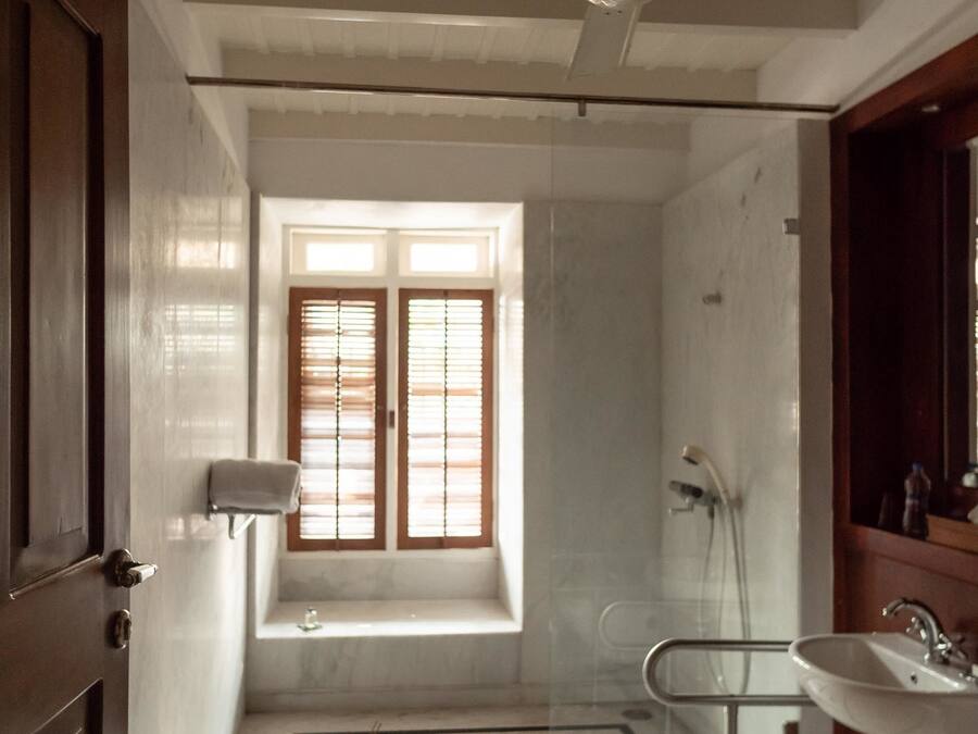 Een badkamer met een bad, een wastafel en een raam met zonwering.