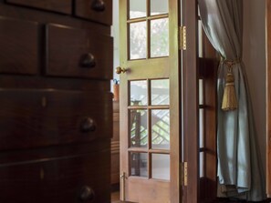 A wooden door with a brass handle and a window with a grid pattern. - Le Colonial 1506 (Kochi)