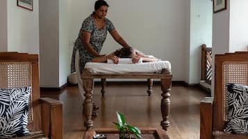 Experience a serene retreat with a massage table, comfortable seating, and a touch of greenery.