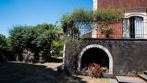 Un patio con un arco de piedra, plantas en macetas y un edificio de fachada roja.