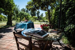 An outdoor dining area with a round glass table, wicker chairs, and a blue tablecloth. - B&B Valleallegra (Gravina di Catania)