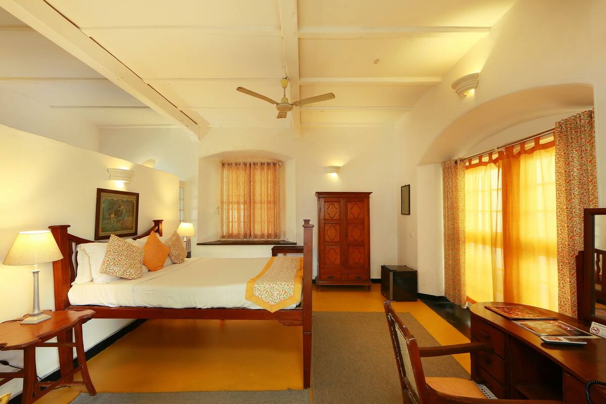 A hotel room with a bed, desk, chair, and wardrobe.