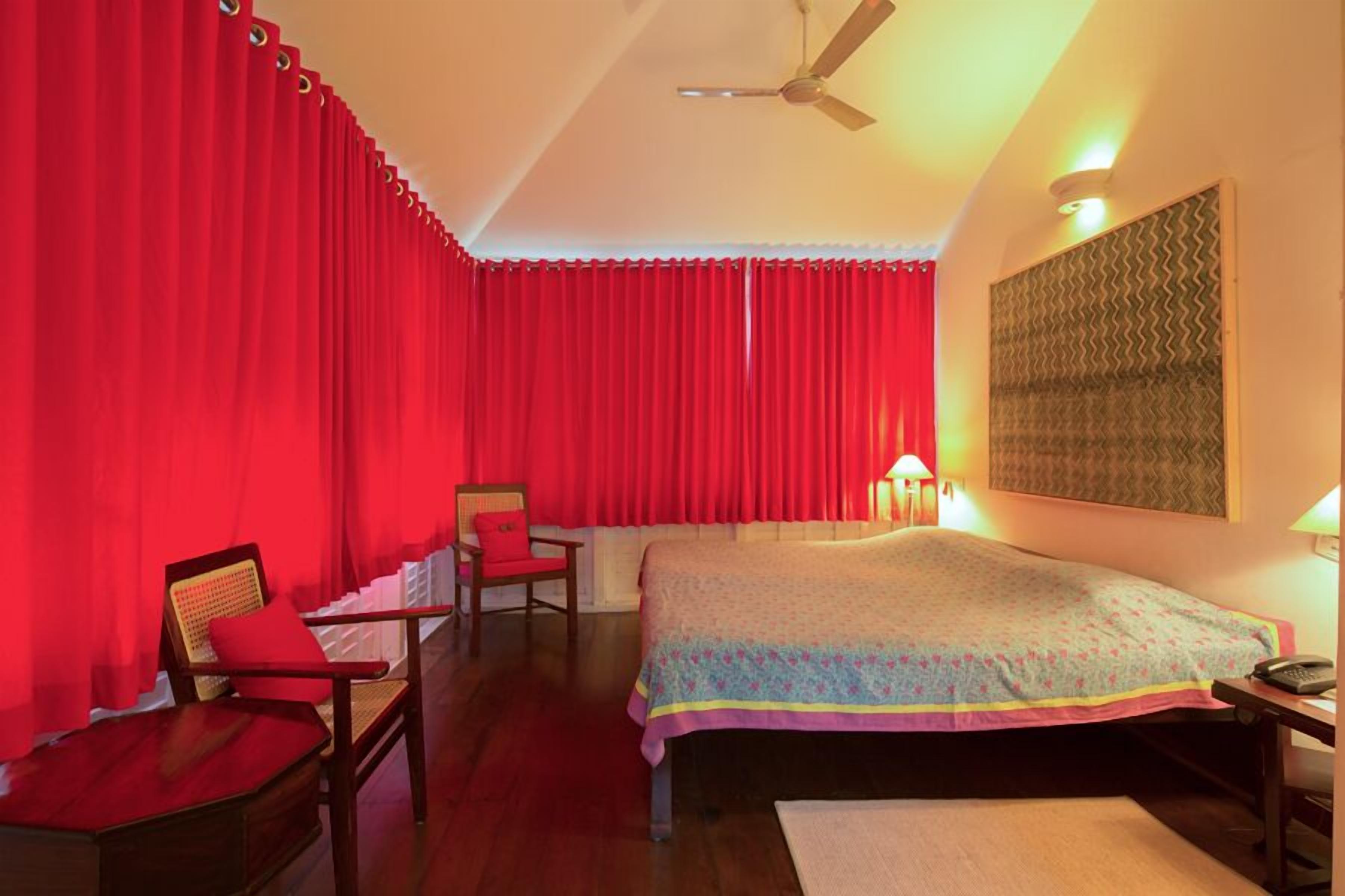 Une chambre d’hôtel avec un lit, une chaise, un bureau et un ventilateur de plafond.