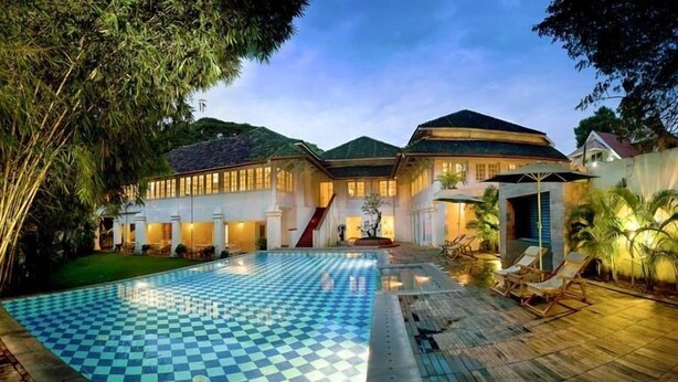 Una casa grande con piscina, un patio cubierto y jardín.