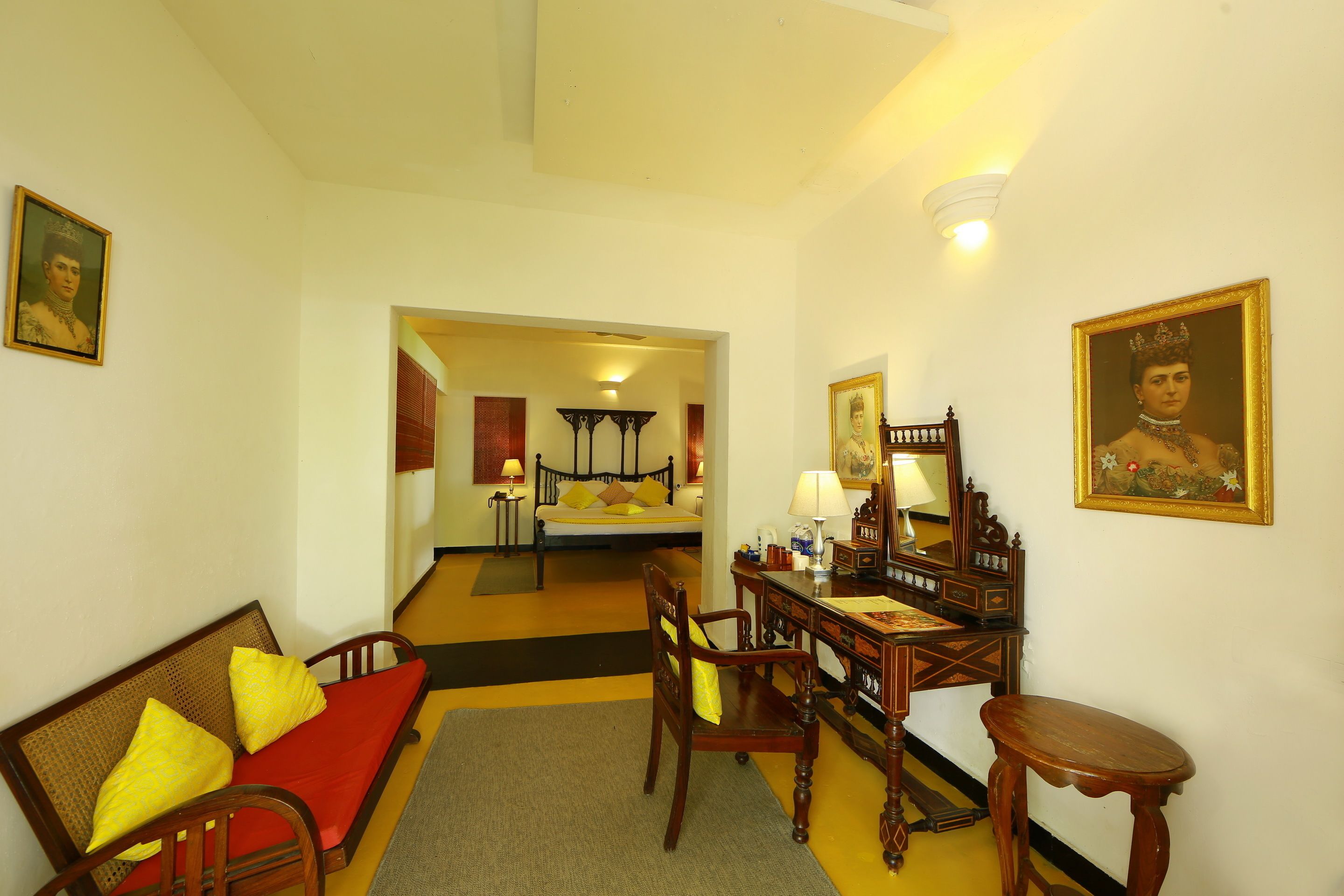 Une pièce comprenant un lit, un bureau, une chaise et un canapé. Il y a deux tableaux accrochés aux murs.
