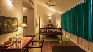 Habitación de hotel con una cama de madera, un escritorio con una silla, una lámpara y un cuadro en la pared.