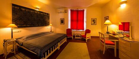 Une chambre d’hôtel avec un lit, un bureau, une chaise et un rideau rouge.