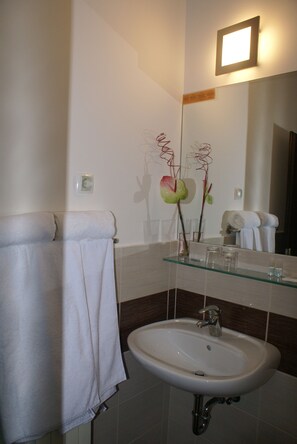 A bathroom with a white sink, glass-topped vanity, and a towel rack with a white towel. - Hotel Prunk (Sezana)