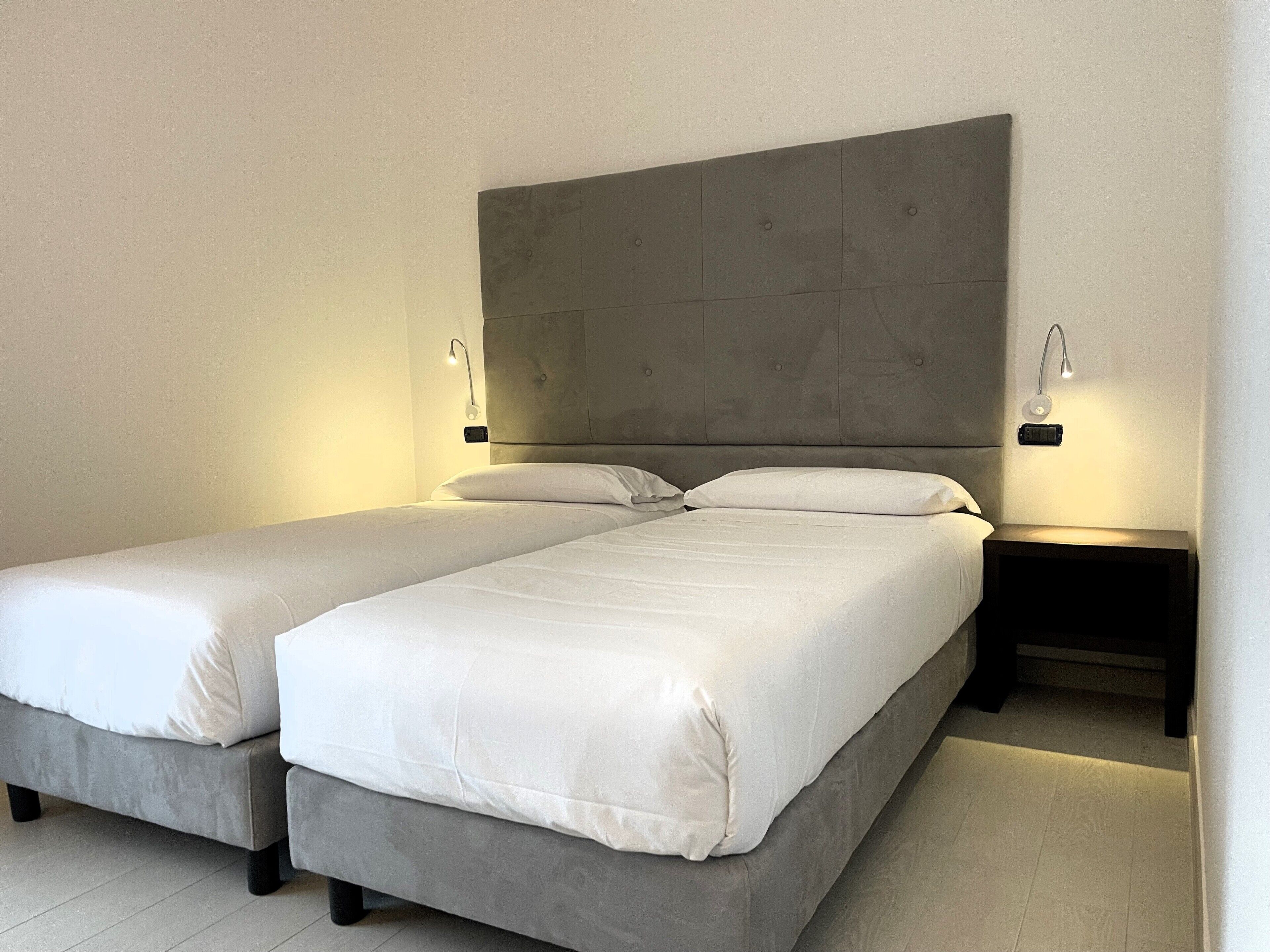 A double bed with a grey headboard and two bedside tables with lamps.