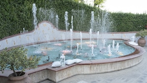 A circular water feature with multiple fountains, surrounded by a low wall and potted plants. - Incontro Hotel & Spa (Ariano Irpino)