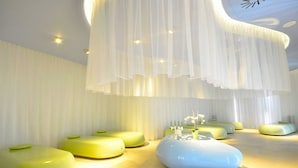 A modern interior with unique green and blue seating areas, a central white table with candles, and a ceiling with hanging white fabric. - Incontro Hotel & Spa (Ariano Irpino)