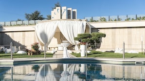 A pool area with a white canopy and a fountain, surrounded by a well-maintained lawn and potted plants. - Incontro Hotel & Spa (Ariano Irpino)