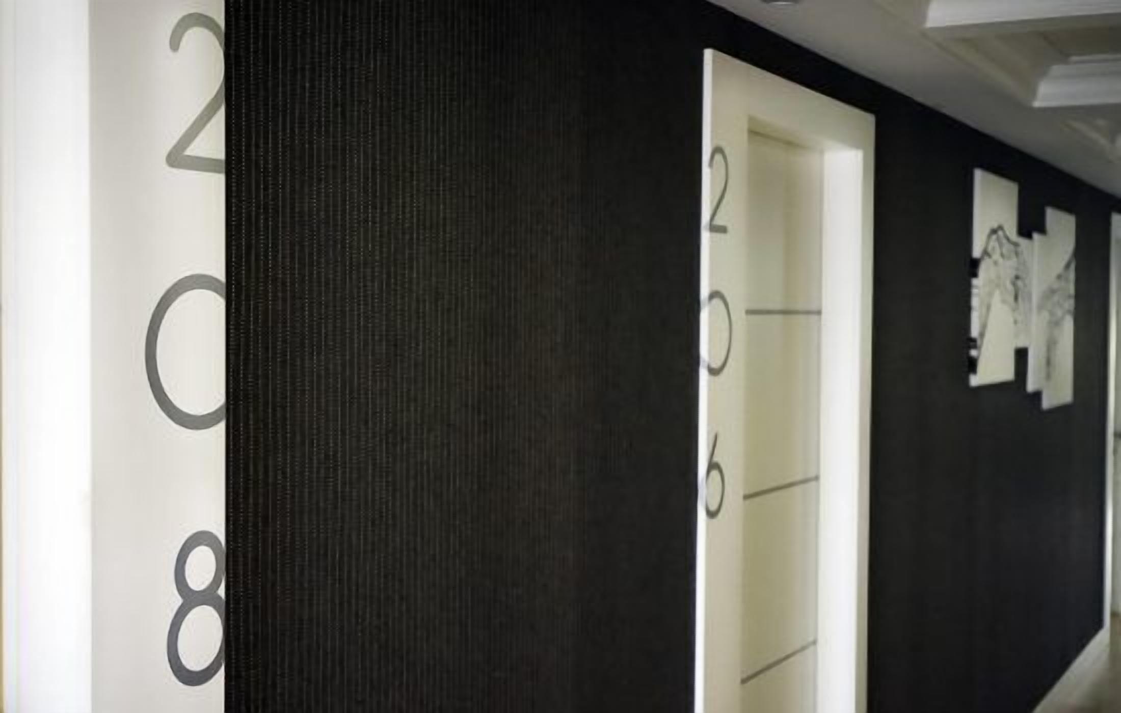 A hallway with numbered doors and a textured wall.