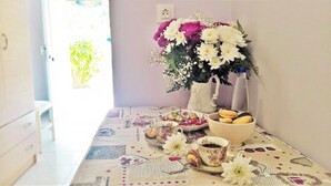 A room with a table set for breakfast, including pastries, a cup of coffee, and a floral arrangement. - Aloni Studios & Apartments (Kefalonia)