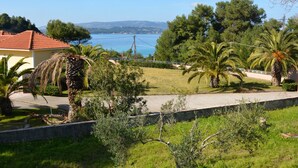 A coastal property with a view of the sea, palm trees, and a red-roofed building. - Aloni Studios & Apartments (Kefalonia)