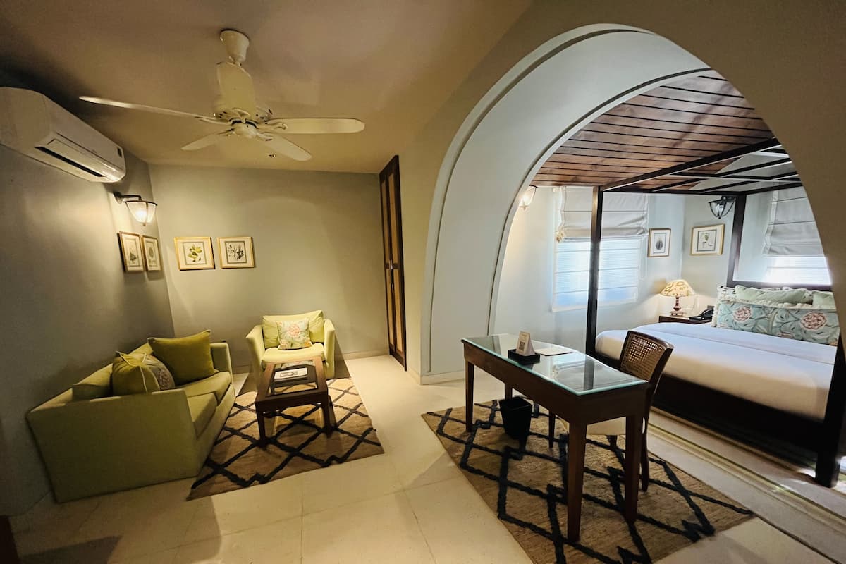 A hotel room with a sofa, armchair, dining table, and a bed.