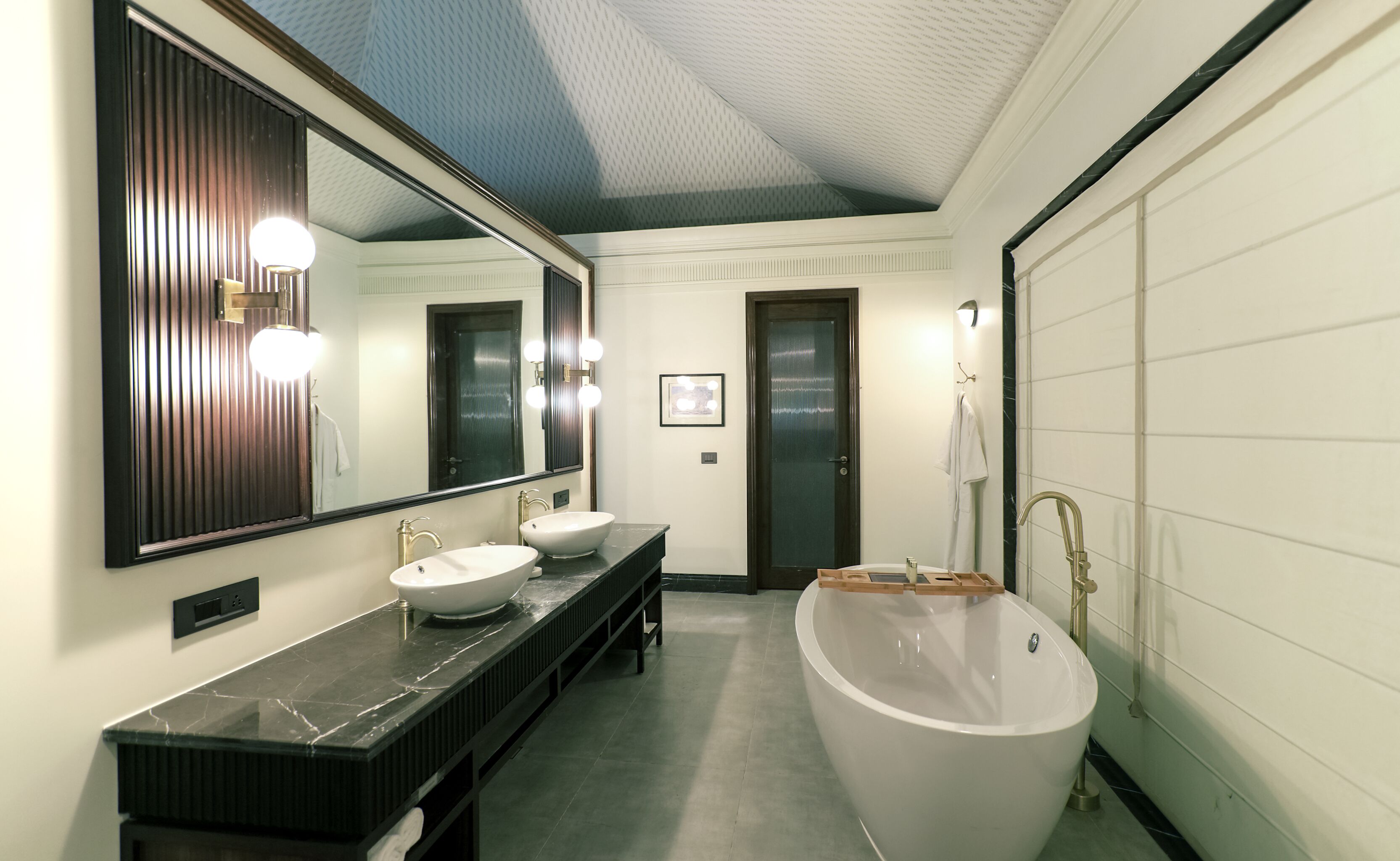 A modern bathroom with a large mirror, two sinks, a bathtub, and a shower.