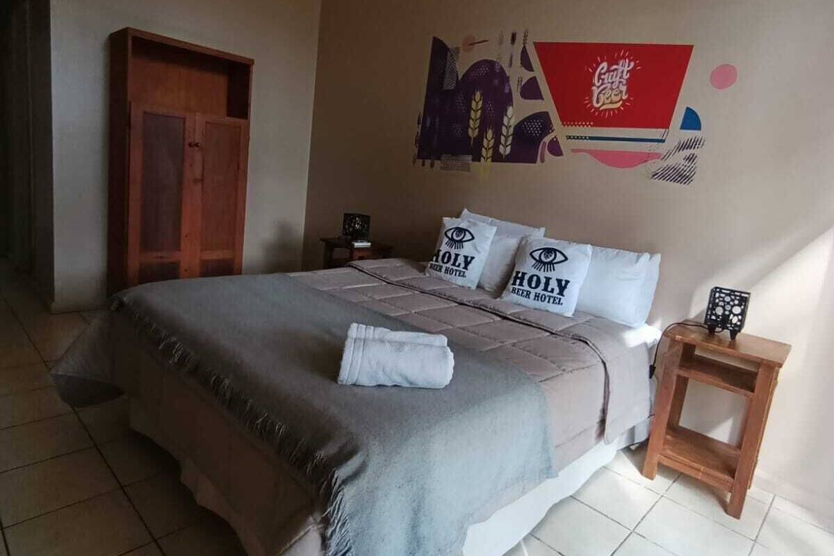 A bedroom with a bed, pillows, a wooden nightstand, and a wall decoration.