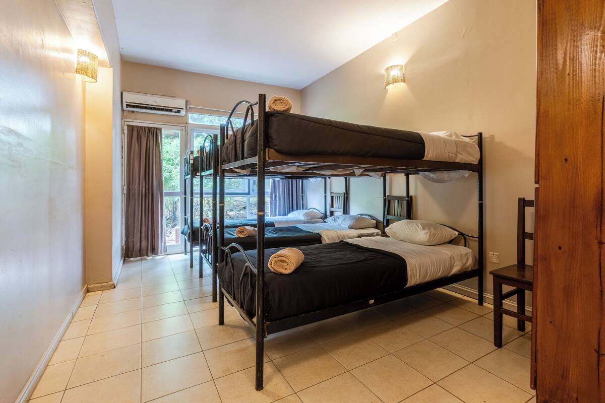 A bunk bed room with a window, curtains, and a chair.
