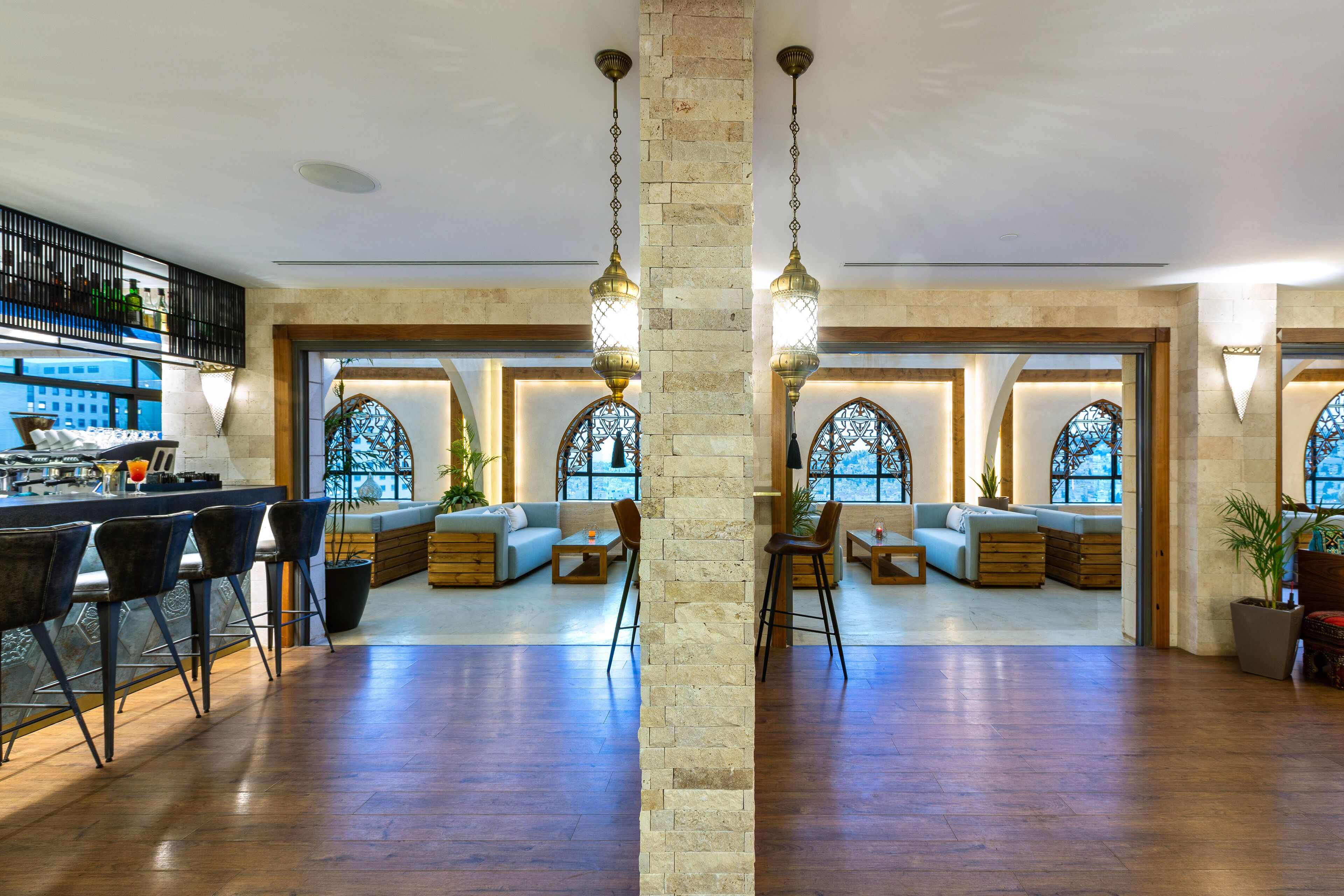 A spacious lobby with a bar area, seating arrangements, and large windows with decorative glass.