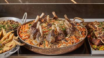 A large wooden serving dish filled with a dish of meat and vegetables, surrounded by other dishes.