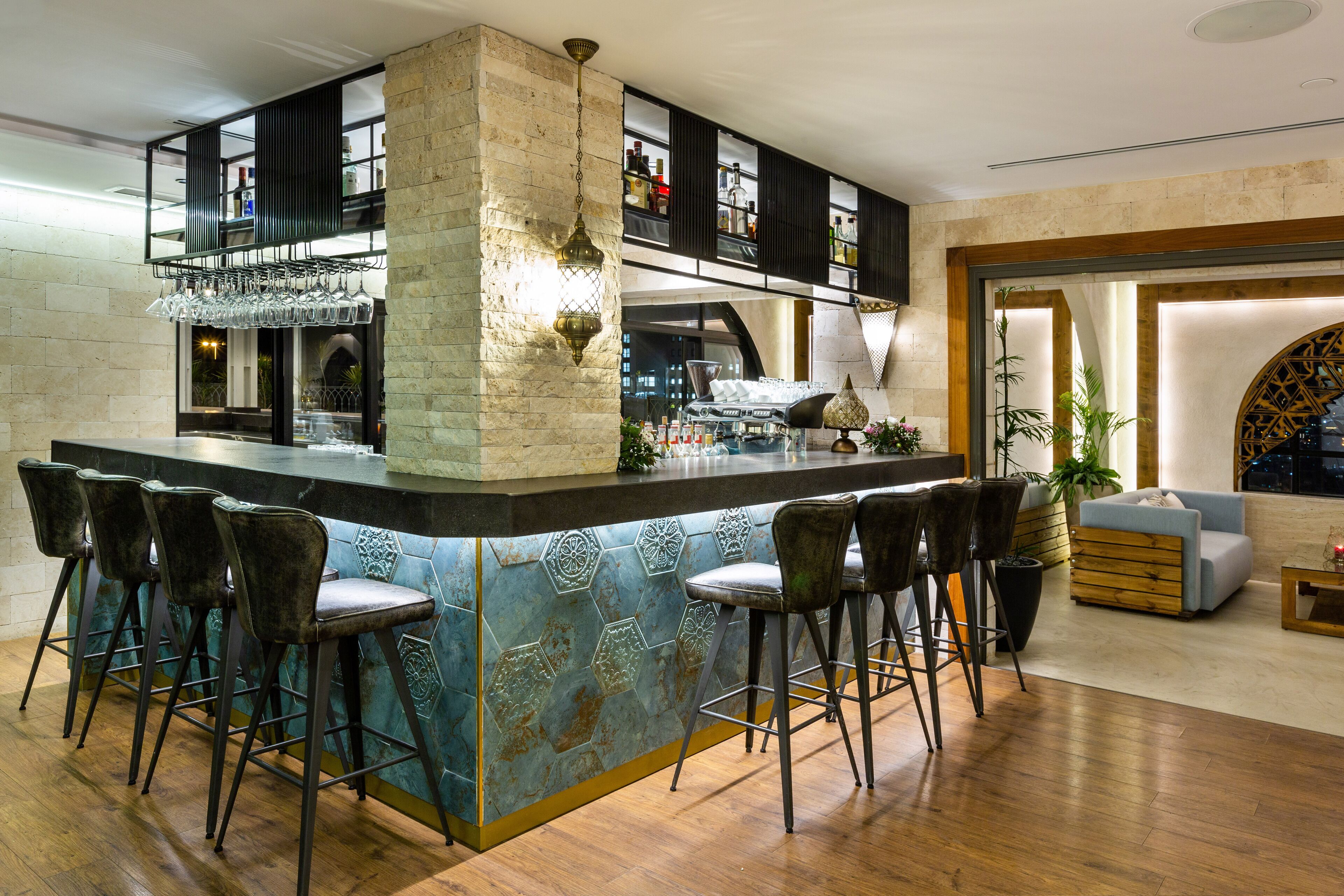 A bar area with a central island, bar stools, and a seating area with a sofa and chairs.
