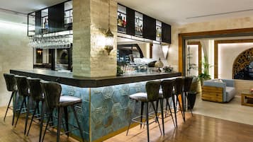 A bar area with a central island, bar stools, and a seating area with a sofa and chairs.