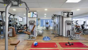 A gym with various exercise equipment, including weight machines, a bench, and dumbbells.