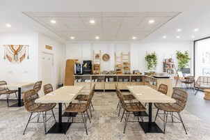 Un comedor moderno con una mesa larga, sillas de mimbre y un mostrador tipo buffet.