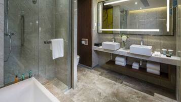 A modern bathroom with a glass-enclosed shower, two sinks, a large mirror, and a bathtub.