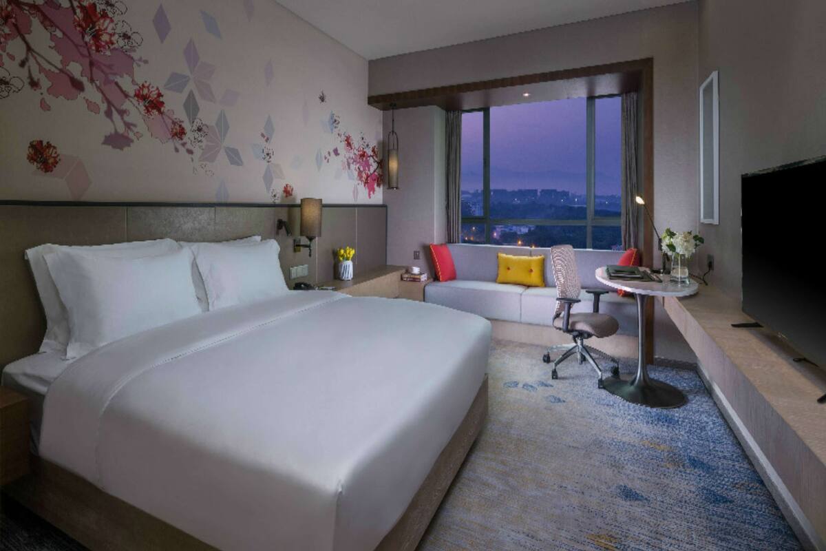 A hotel room with a large bed, a sofa, a small table, and a TV.