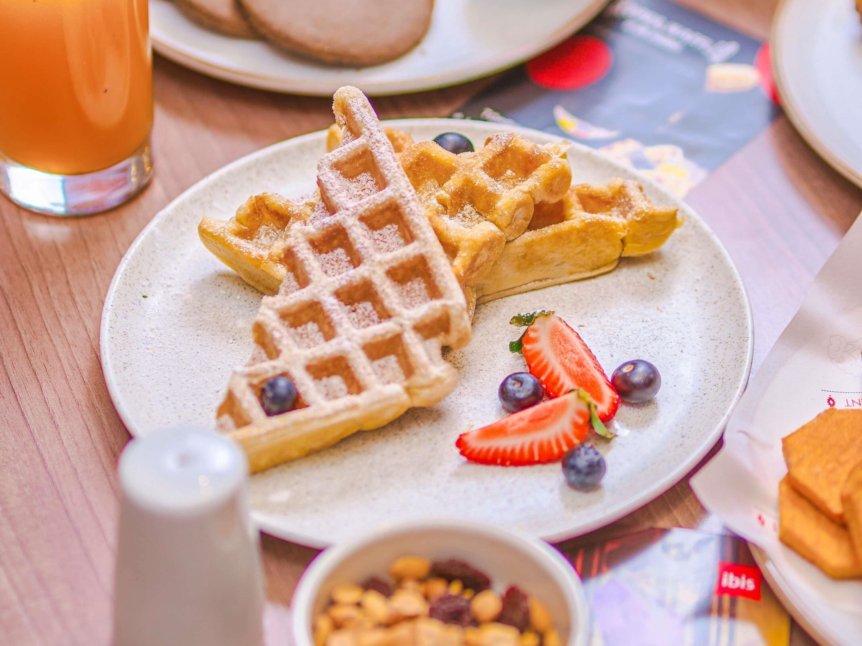 Un plato con waffles, fresas y arándanos sobre una mesa.