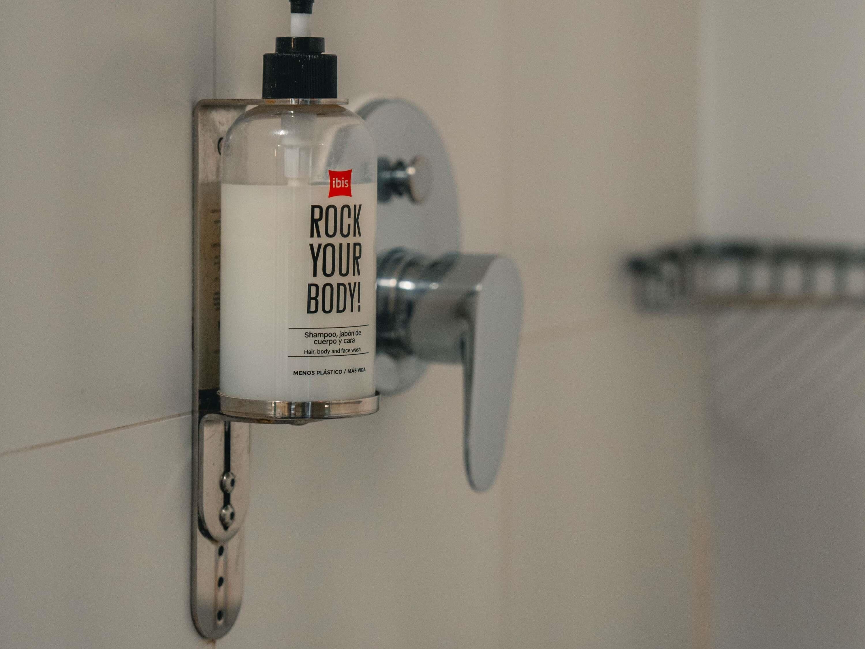Ein Badezimmer mit einem an der Wand montierten Seifenspender mit der Aufschrift "ROCK YOUR BODY!" und einem Handtuchhalter.