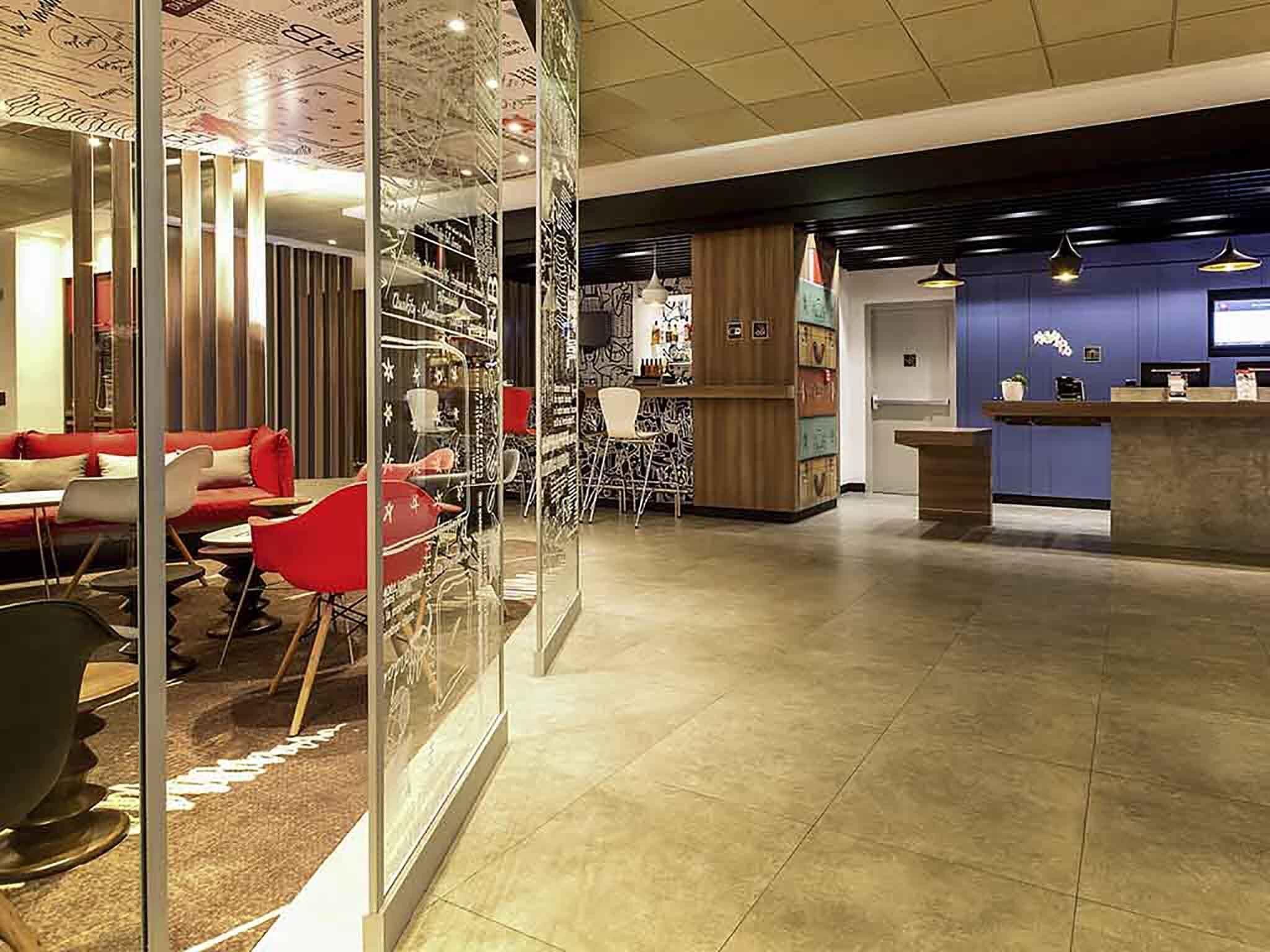 Una moderna hall d'albergo con reception, area lounge e pareti divisorie in vetro.
