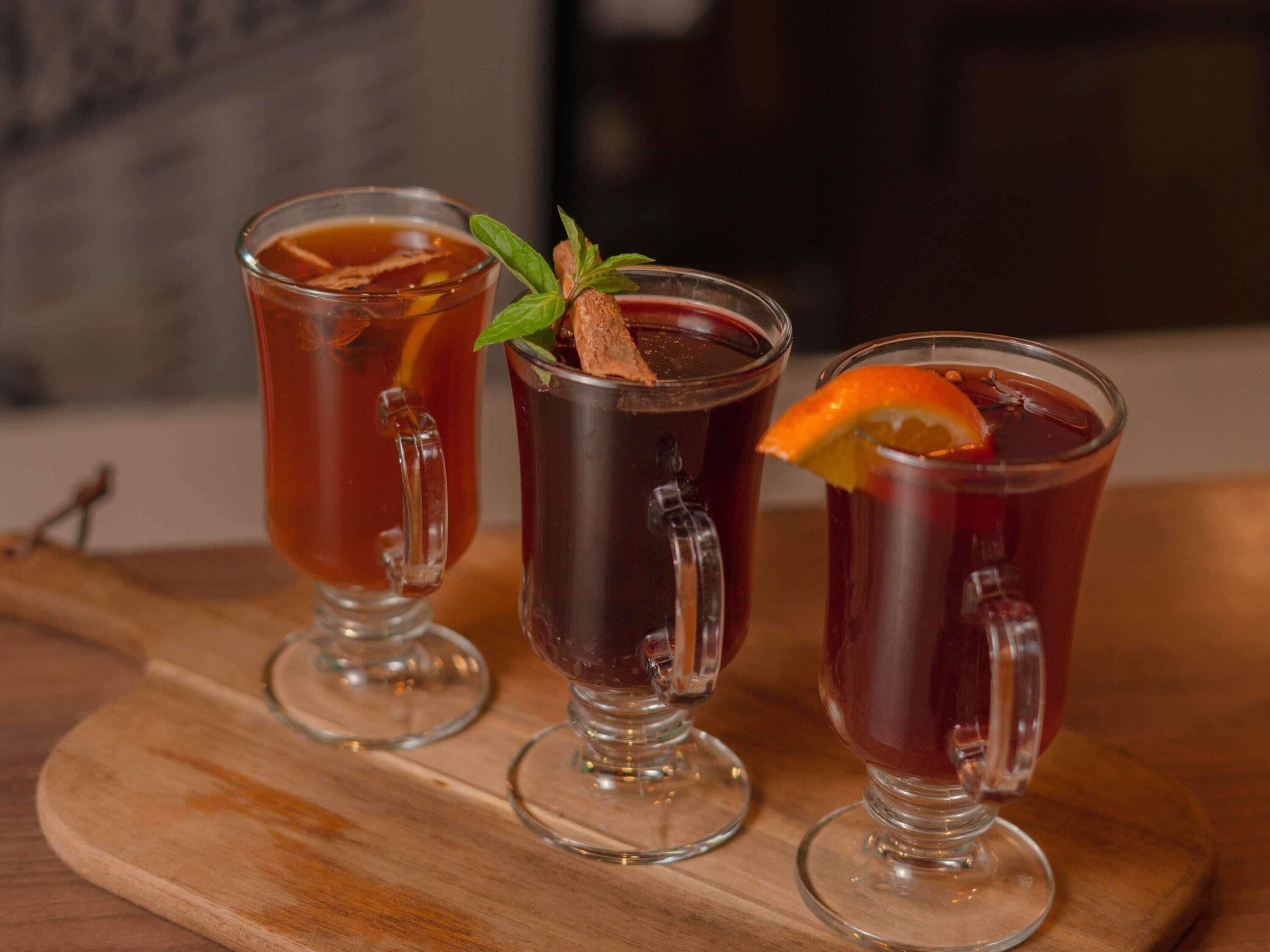 Three glasses of tea on a wooden board.