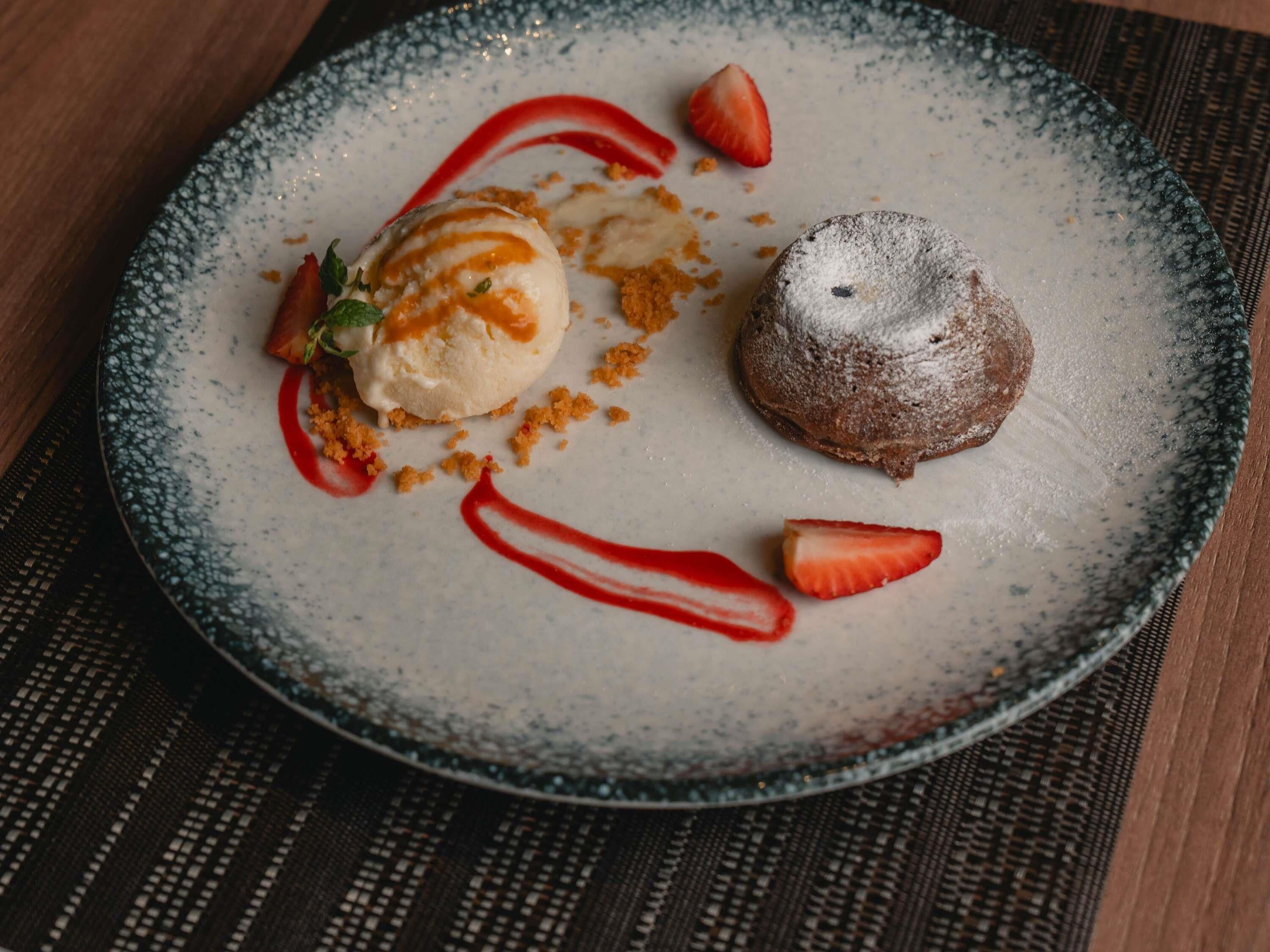 A dessert plate with a scoop of ice cream, a chocolate cake, and strawberries.