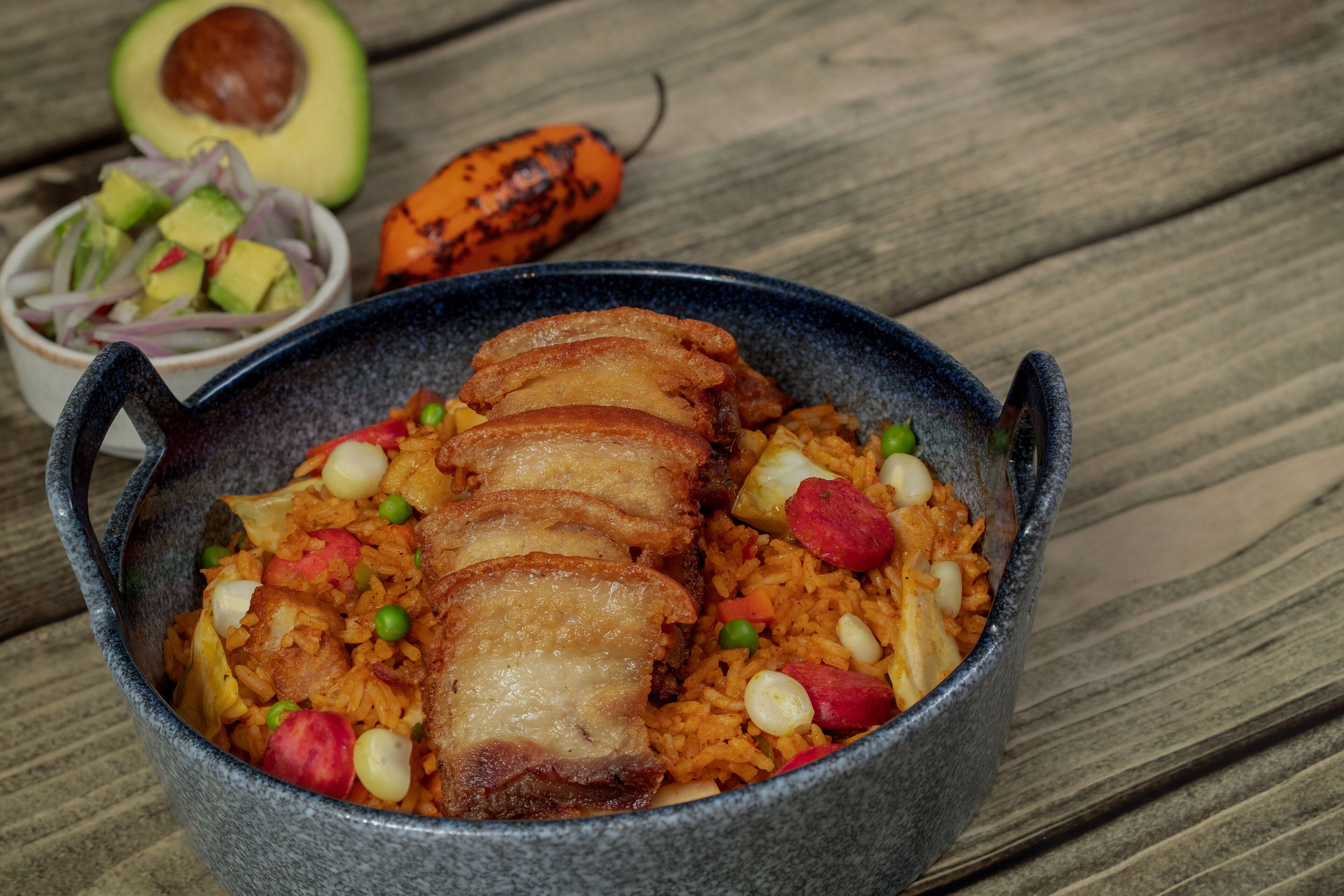 Un tazón de arroz con carne y verduras sobre una mesa de madera.