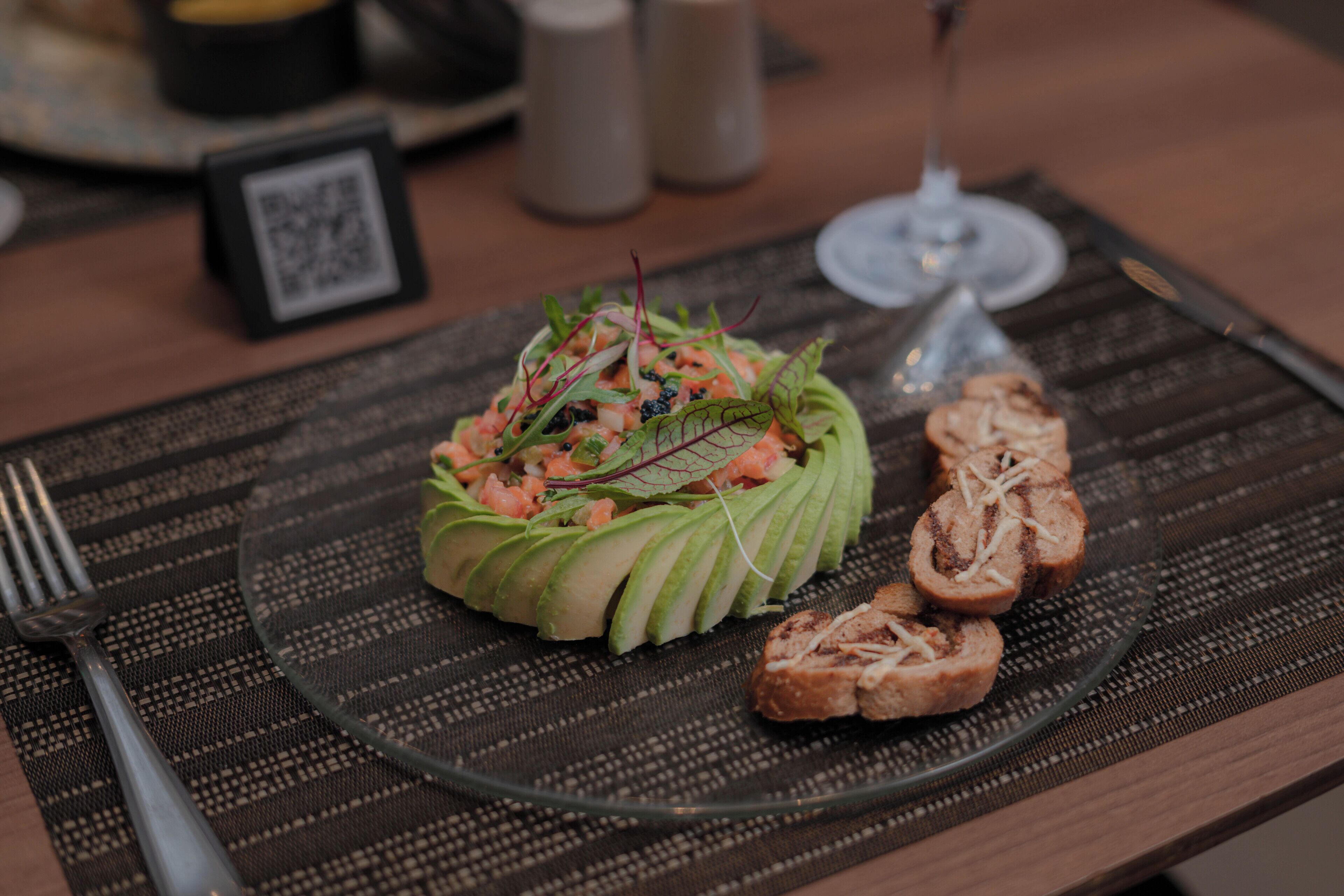 A plate of food with a salad and bread on a placemat.