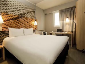 A hotel room with a large bed, a desk with a laptop, a chair, and a window with curtains. - ibis Lima Reducto Miraflores (Lima)
