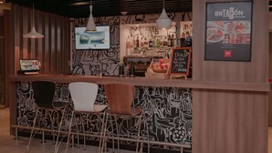 Een bar met een toonbank, barstoelen en een menukaart.