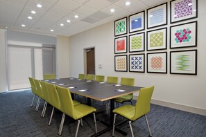A conference room with a long table, green chairs, and framed artwork on the walls. - Holiday Inn Express & Suites Brookshire - Katy Freeway by IHG (Brookshire)