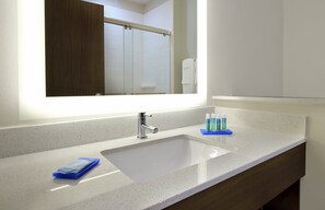 A bathroom with a white sink, a mirror, and toiletries on the counter. - Holiday Inn Express & Suites Brookshire - Katy Freeway by IHG (Brookshire)