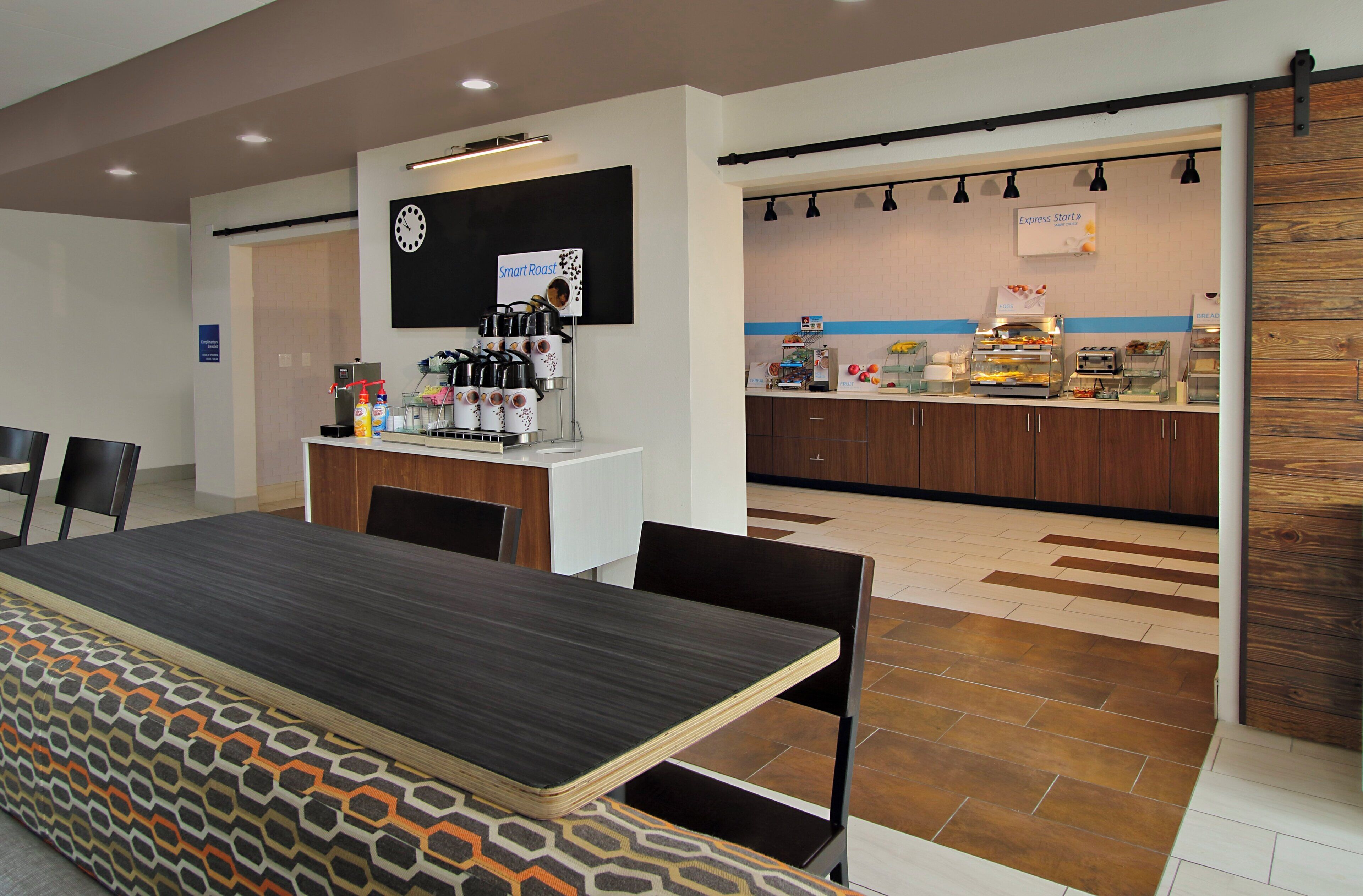 Eine moderne Küche mit einer Kaffeestation, einem Buffetbereich und einer Sitzecke mit gemustertem Tischlein.