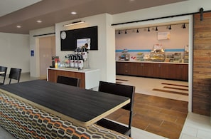 A modern kitchen with a coffee station, a buffet area, and a seating area with a patterned tablecloth. - Holiday Inn Express & Suites Brookshire - Katy Freeway by IHG (Brookshire)