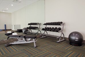 A gym with exercise equipment including a treadmill, weight benches, and dumbbells. - Holiday Inn Express & Suites Brookshire - Katy Freeway by IHG (Brookshire)