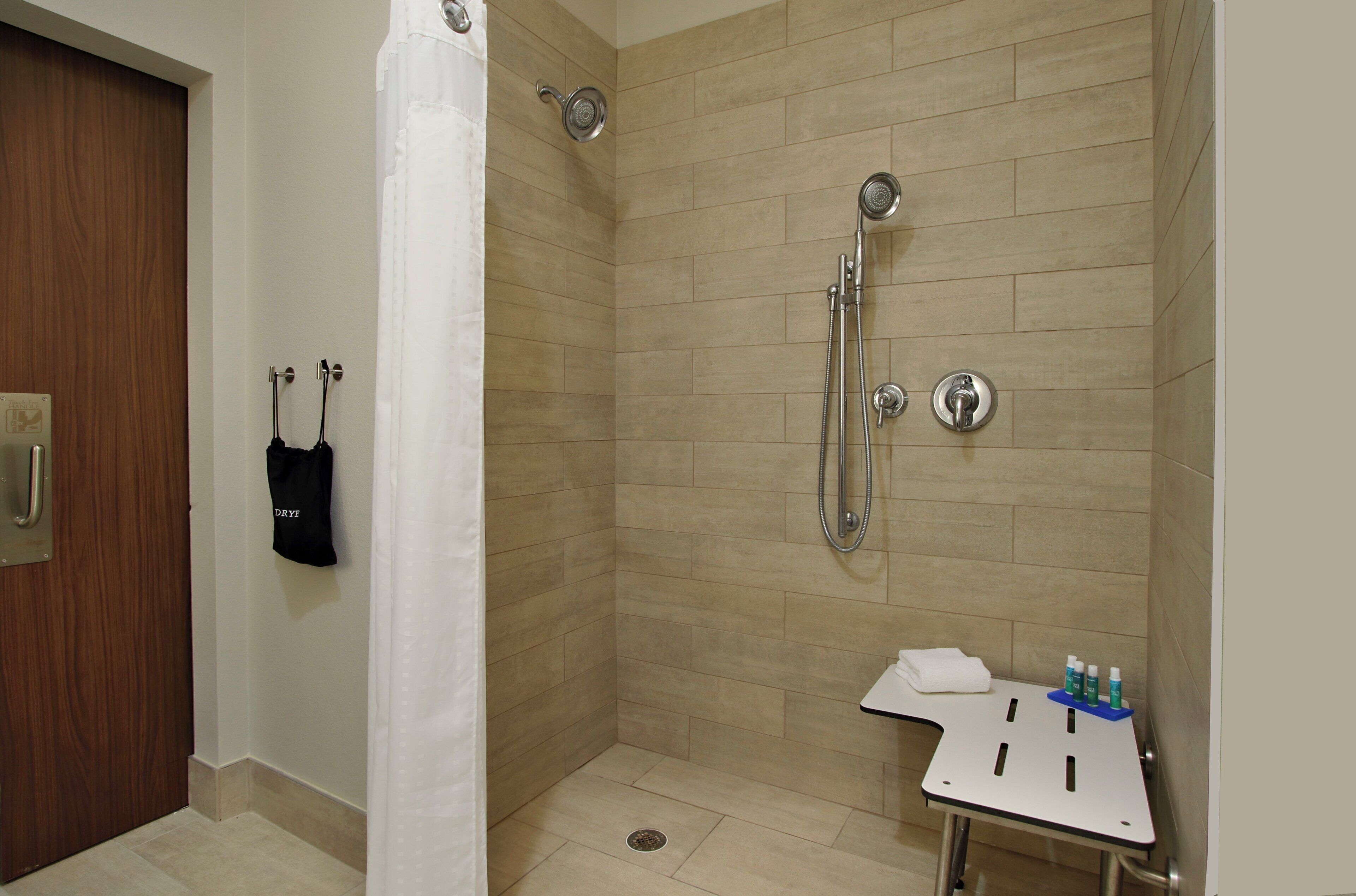 A shower area with a handheld showerhead and a wall-mounted faucet.
