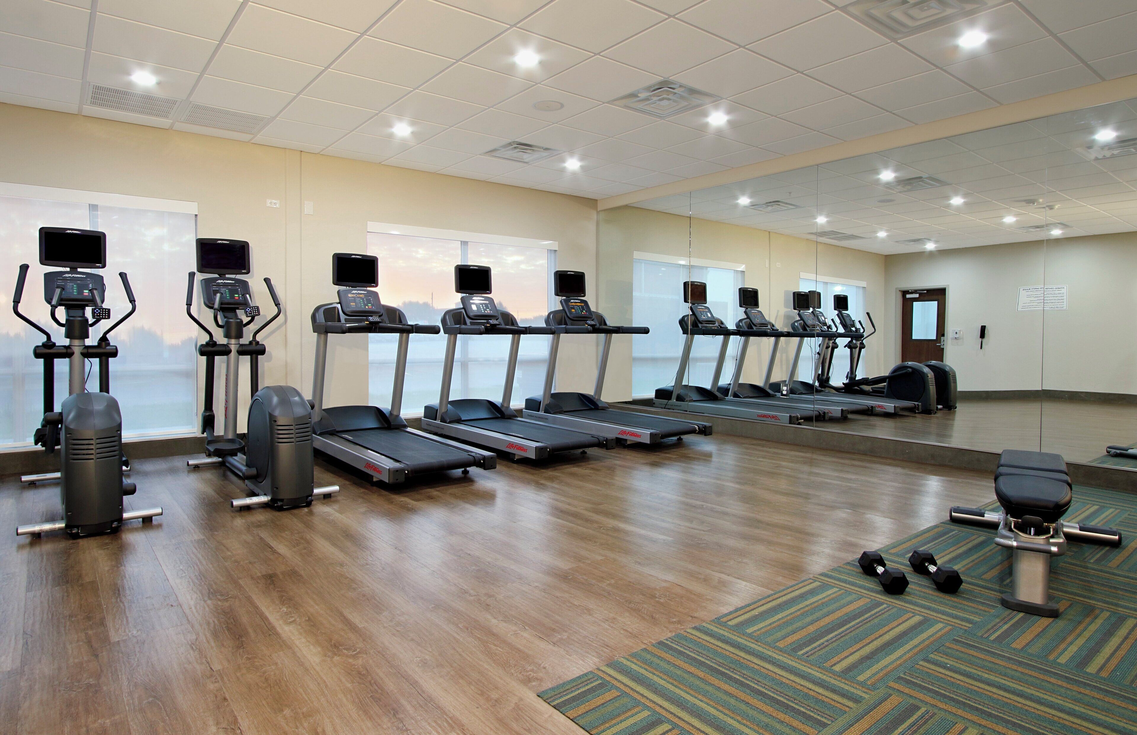 Ein Fitnessstudio mit Laufbändern, Crosstrainern und Kurzhanteln.