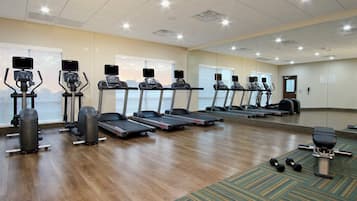 Ein Fitnessstudio mit Laufbändern, Crosstrainern und Kurzhanteln.